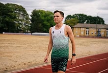 British middle-distance runner Henry McLuckie training outdoors on a track field.