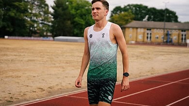 British middle-distance runner Henry McLuckie training outdoors on a track field.