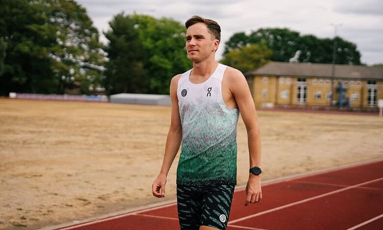 British middle-distance runner Henry McLuckie training outdoors on a track field.