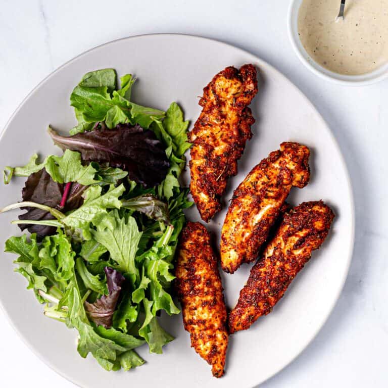 air fryer chicken tenders on a plate with a side of salad.
