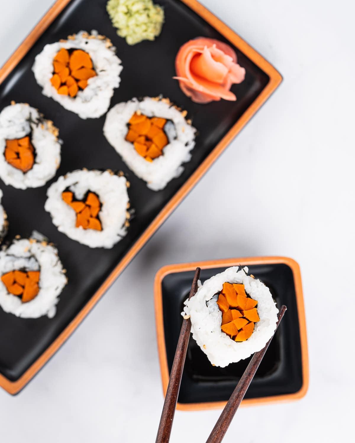 Chopsticks holding gobo sushi and dipping into soy sauce.
