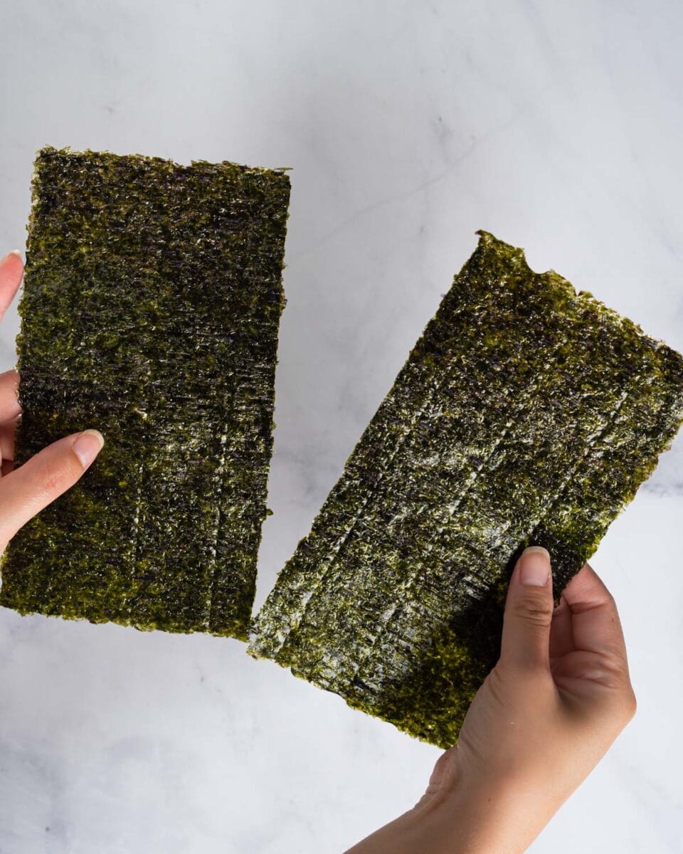 Hands holding two halves of seaweed.