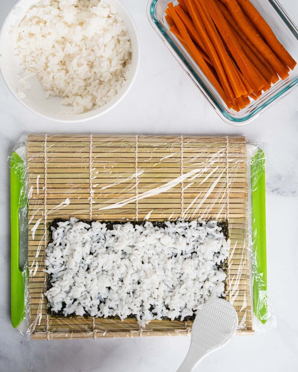 Spreading a layer of rice onto the seaweed.