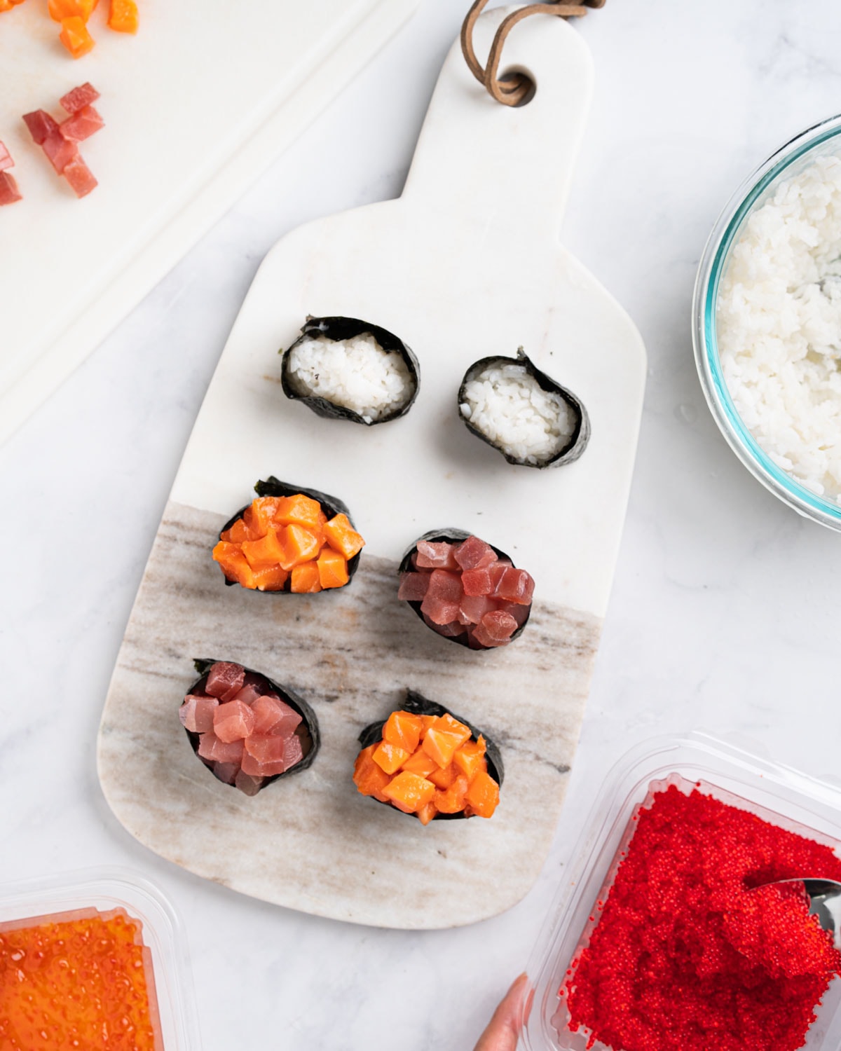 Assembling the gunkan with toppings. Rice and toppings surrounding the marble board.