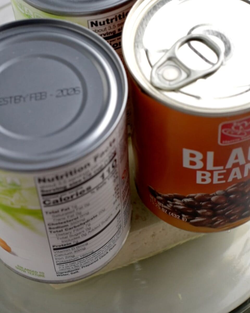 Tofu between two glass plate with cans weighing it down.