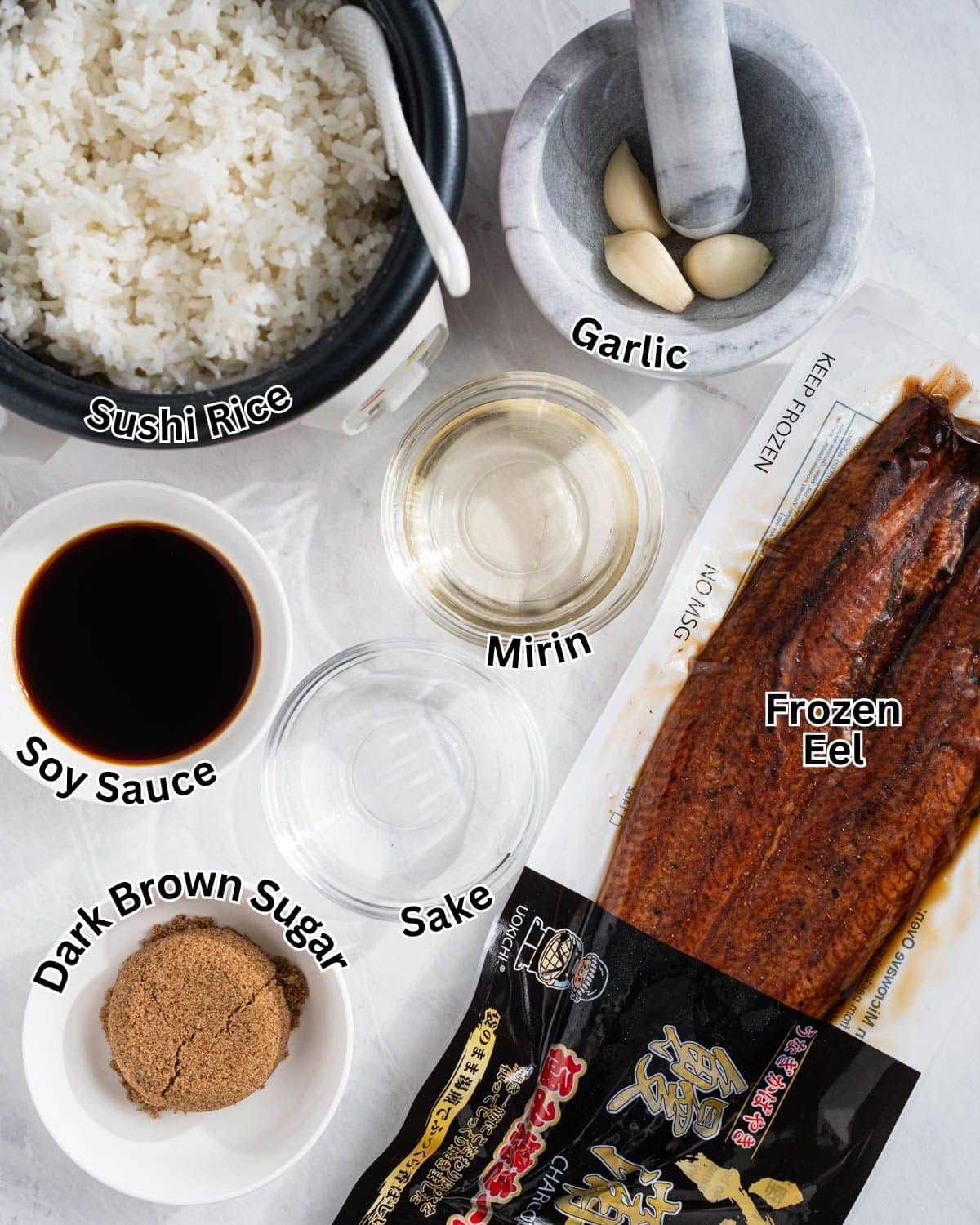 Ingredients needed to make unagi don with labels for each item: sushi rice, frozen eel, garlic, soy sauce, mirin, sake, and dark brown sugar.