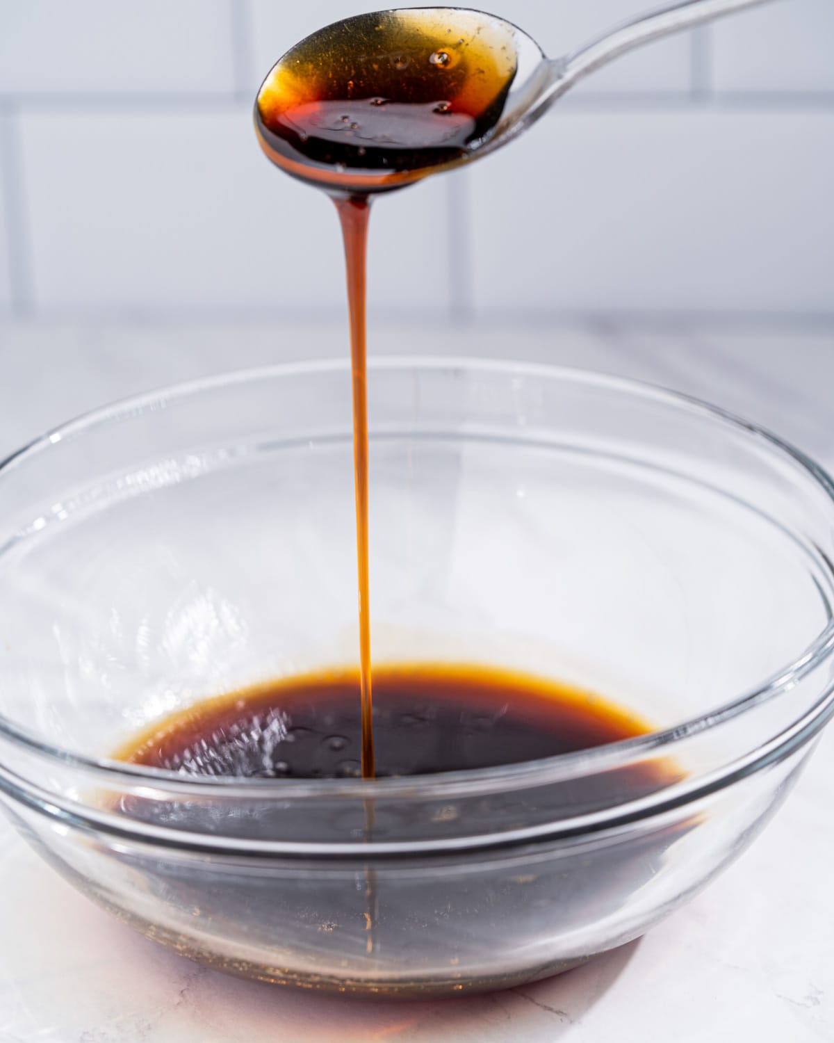 bowl of unagi sauce with spoon drizzling the sauce down to show smooth thick consistency.