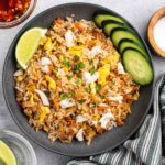 Plate of crab fried rice with side of lime wedges, sliced cucumbers and spicy fish sauce.