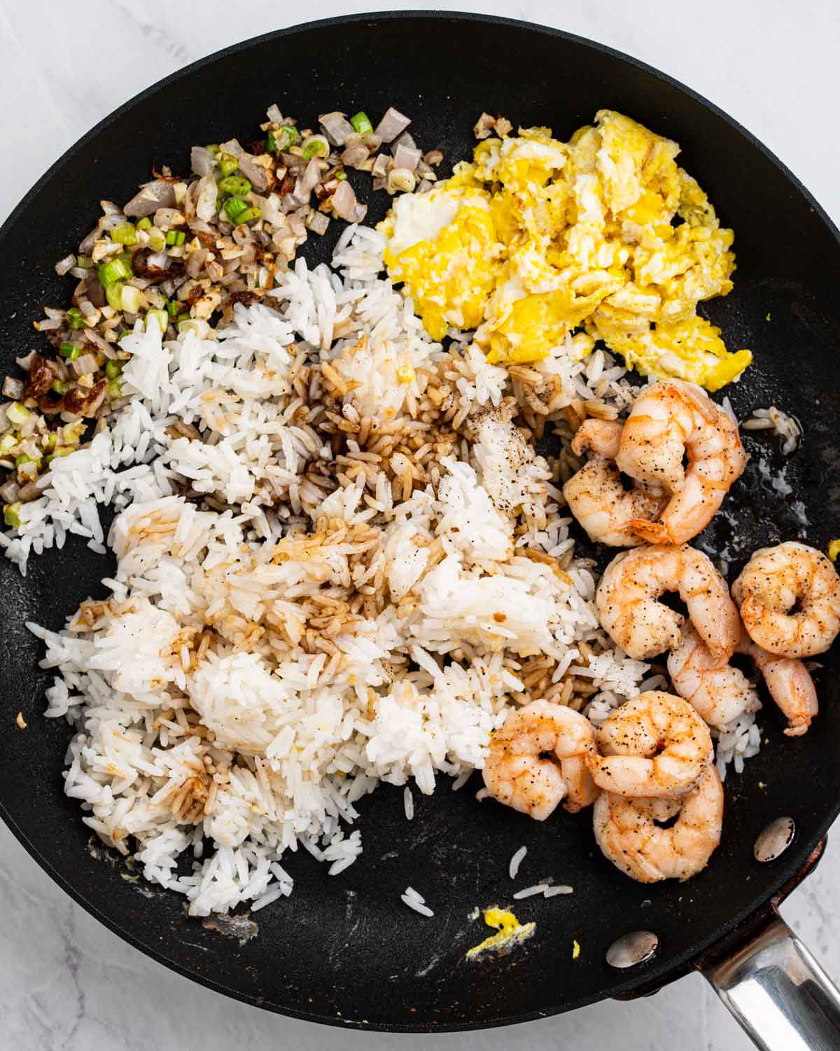 Pan with sections of sautéed shrimp, rice with seasoning on top, vegetables and eggs.