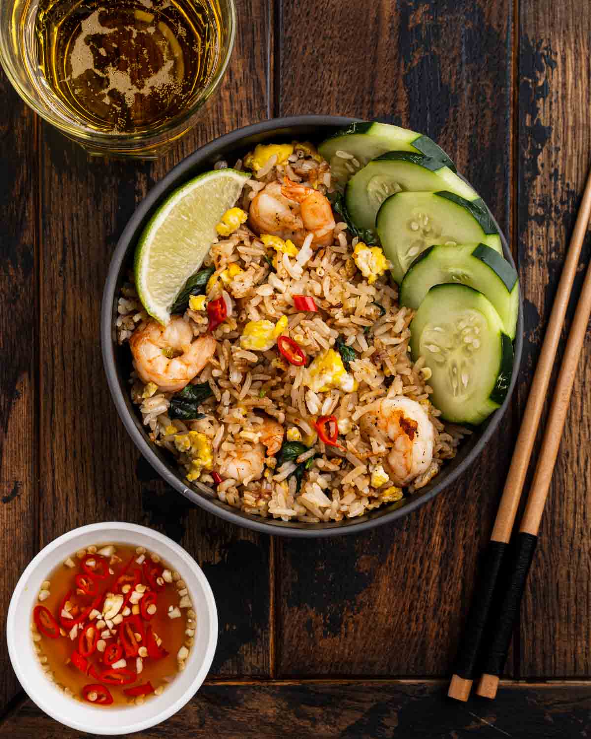 Dark wooden table set up with Thai fried rice in a bowl.