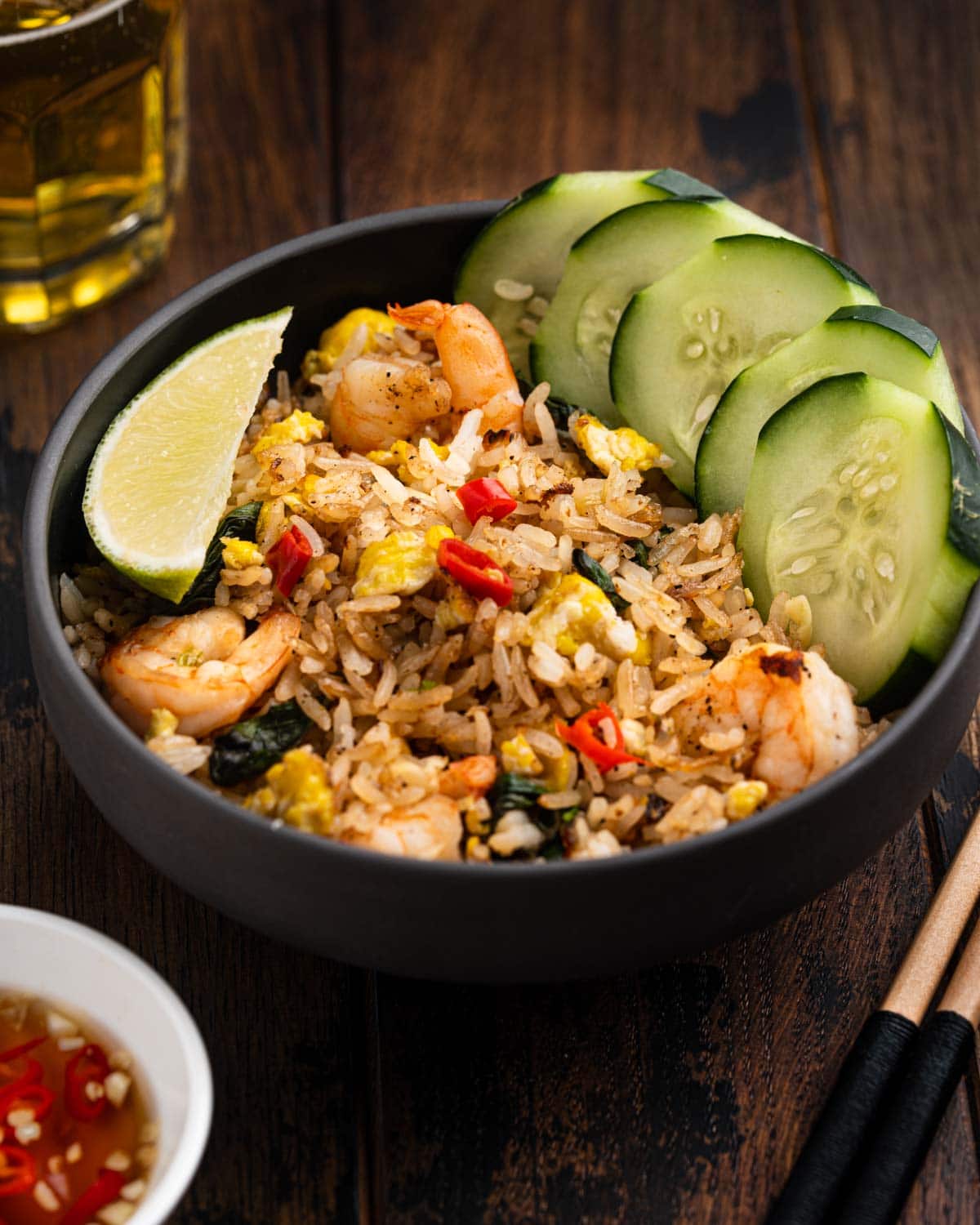 45 degree angle of Thai fried rice in a bowl with fish sauce on the side and chopsticks.