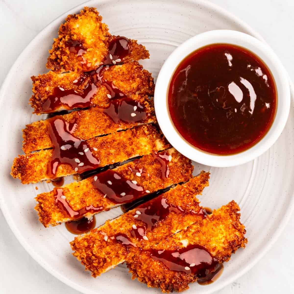 Plate of chicken katsu with sauce.
