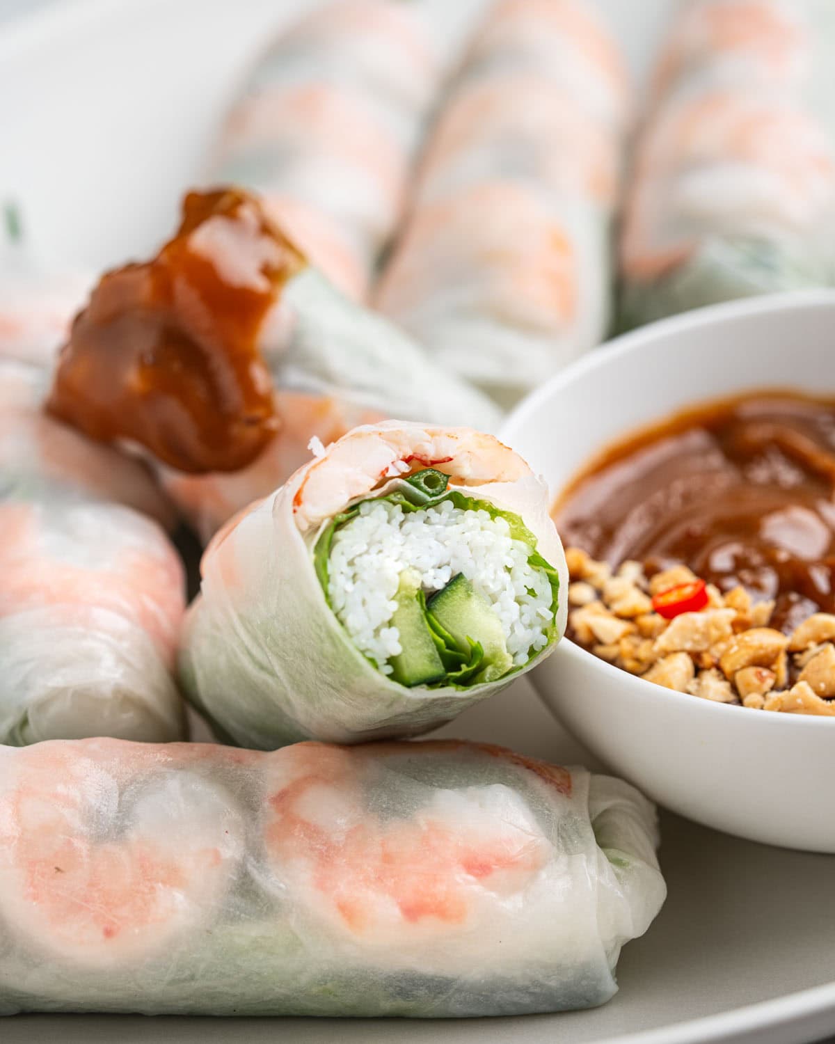 Cross section of spring roll to show inside. Other half dipped in peanut sauce.