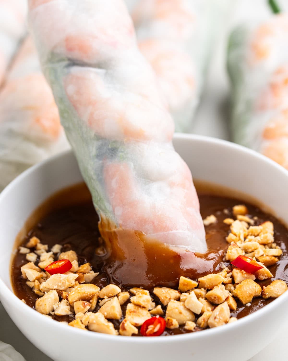 dipping spring roll into peanut sauce.