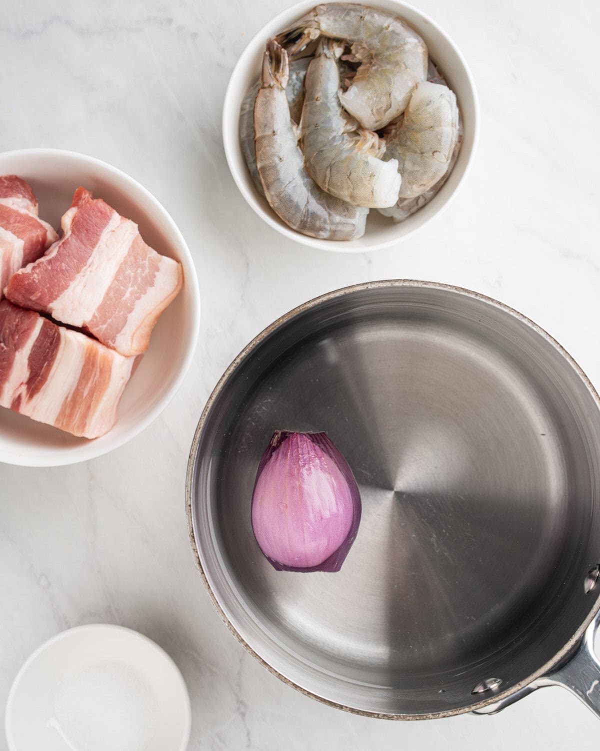 pot of boiling water with bowls of raw pork belly and shrimp.