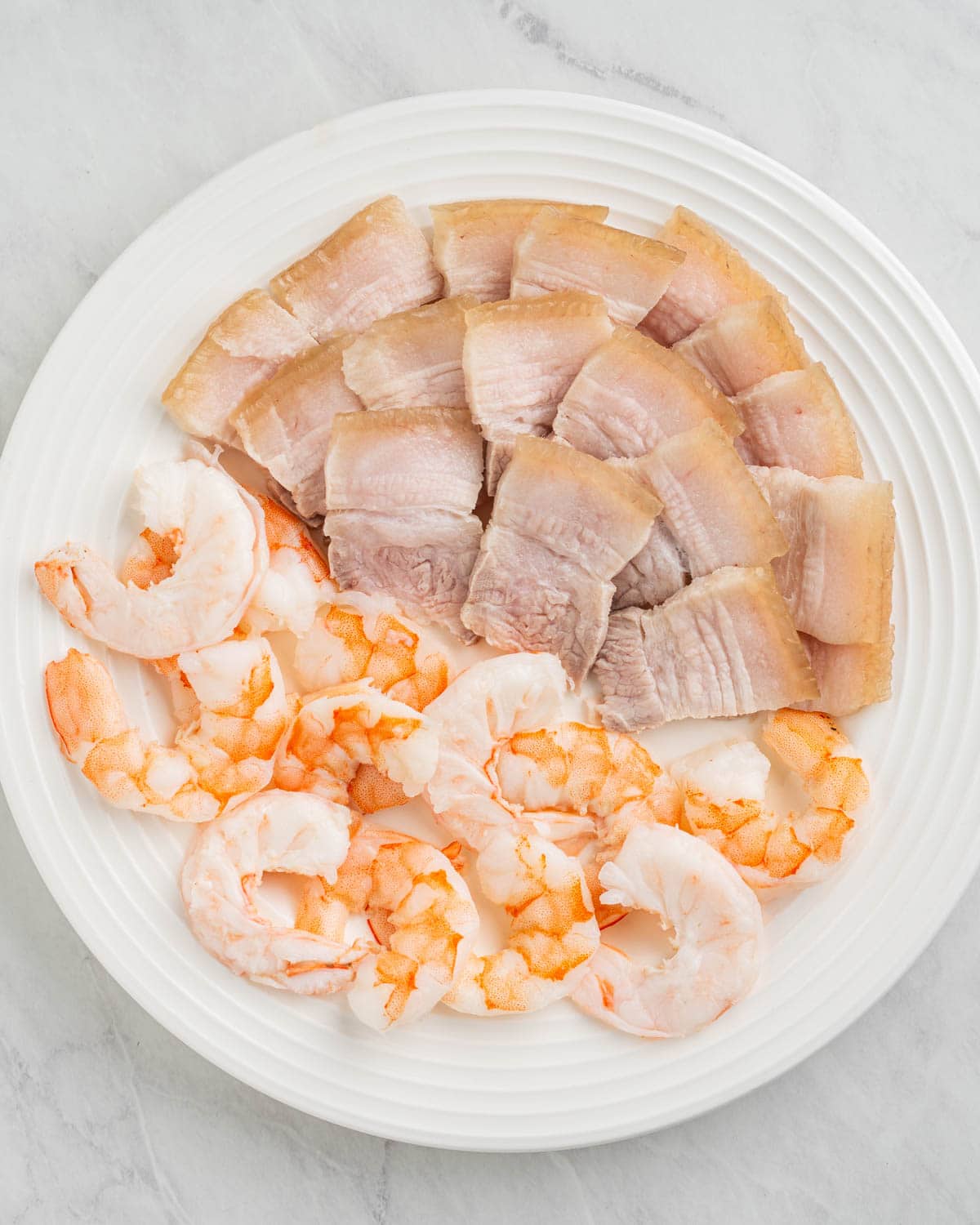 plate of cooked sliced pork belly and shrimp.
