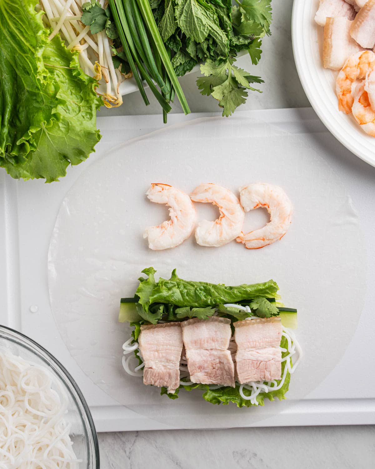 pork belly and shrimp on rice paper along with other ingredients for spring rolls.