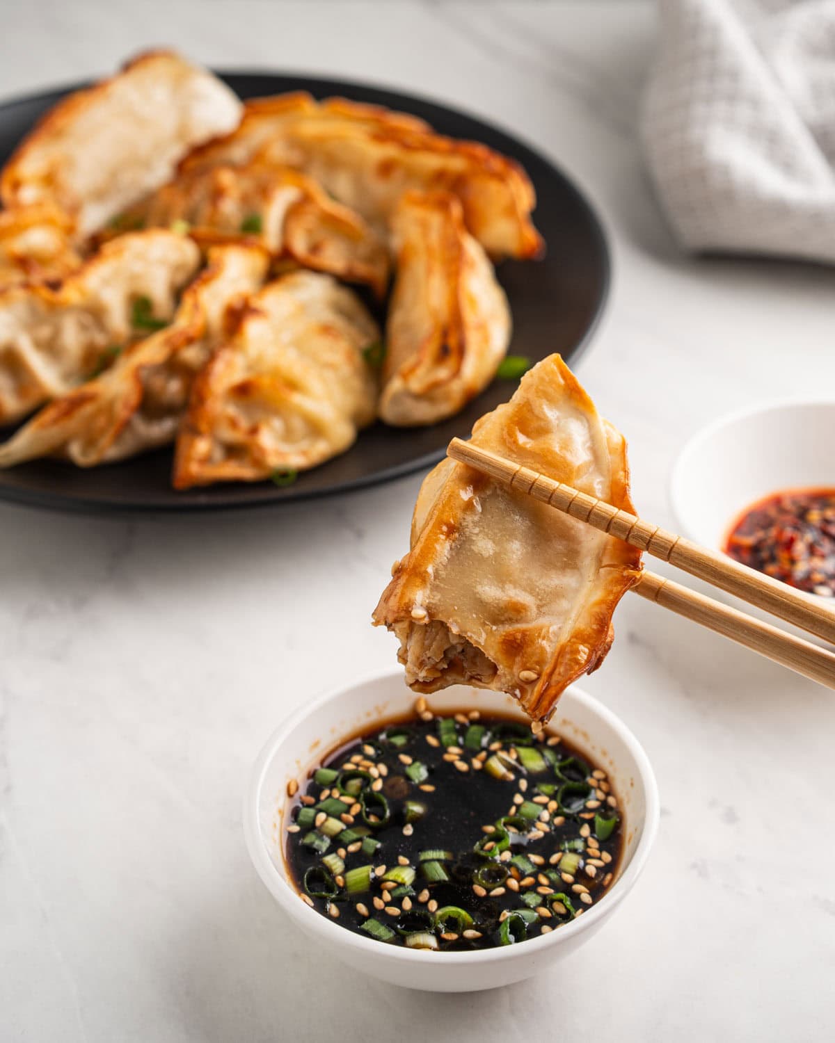 chopsticks dipping air fryer dumplings into soy sauce.