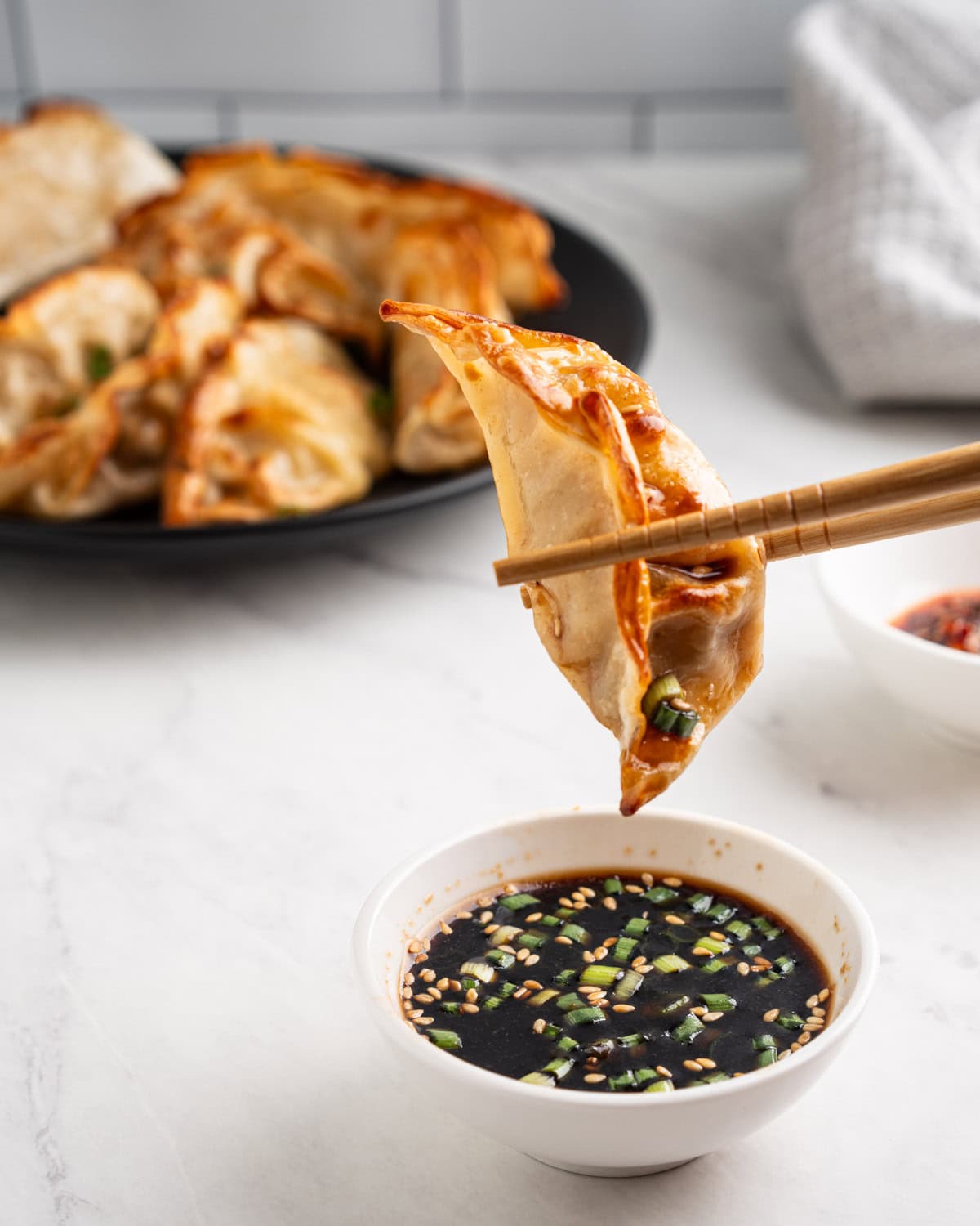 chopsticks dipping air fried dumplings into soy sauce.