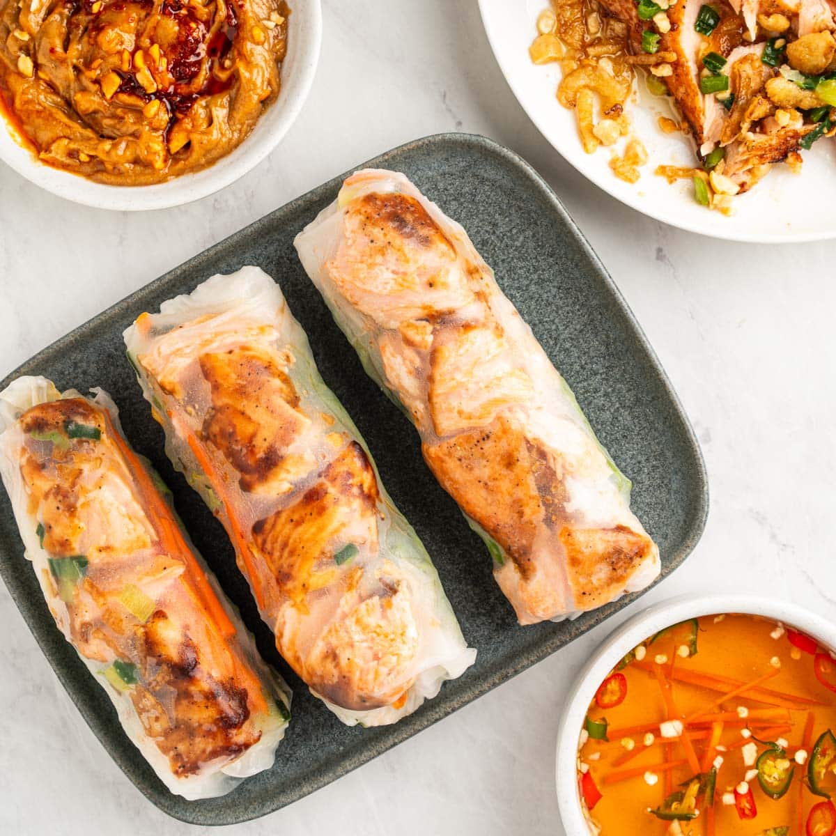 Plate of salmon spring rolls with fish sauce dip and peanut sauce.