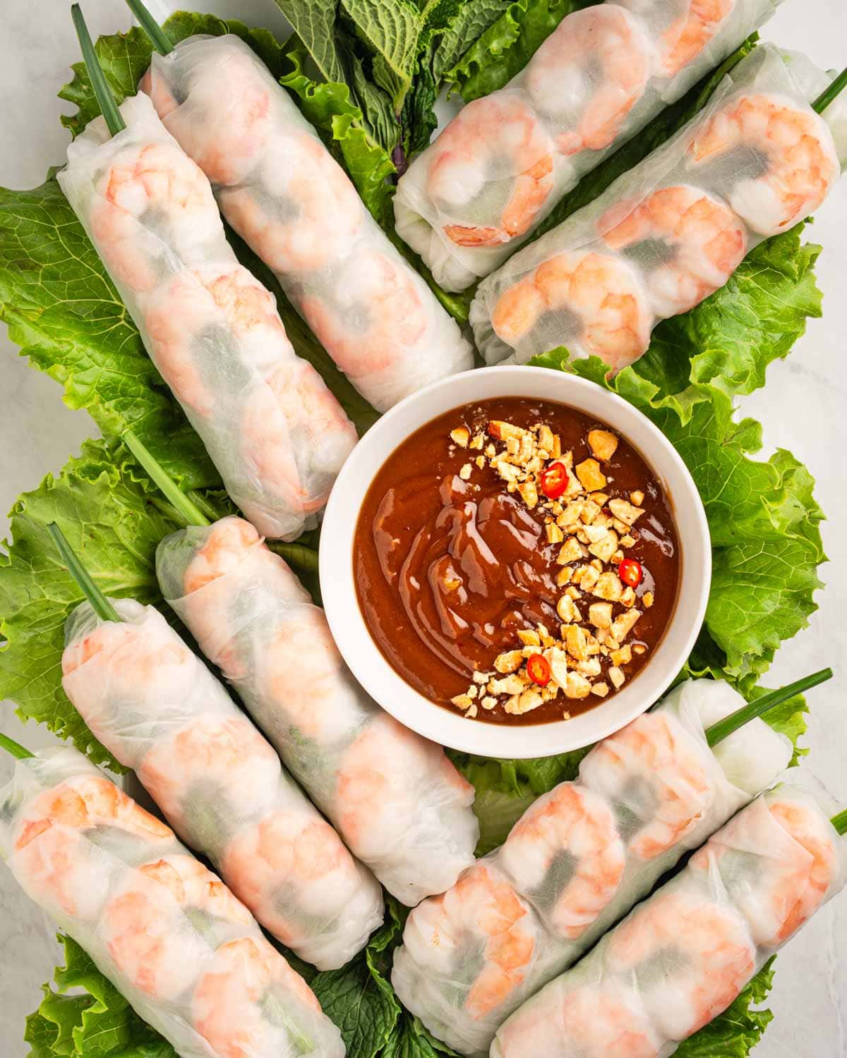 Vietnamese spring rolls goi cuon on a plate of lettuce and herbs.