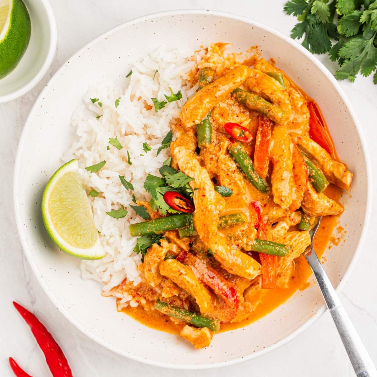 plate of Thai coconut chicken curry with green beans and red peppers over rice.