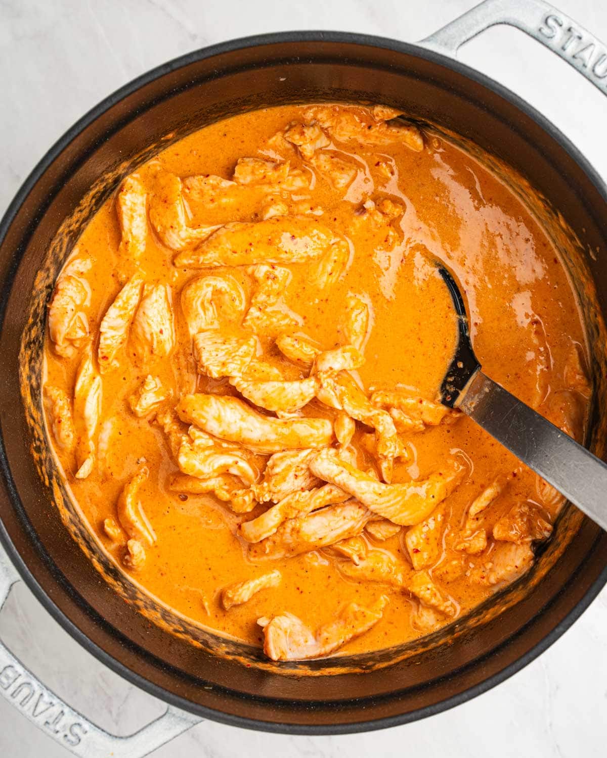 Cooked sliced chicken in coconut curry sauce.