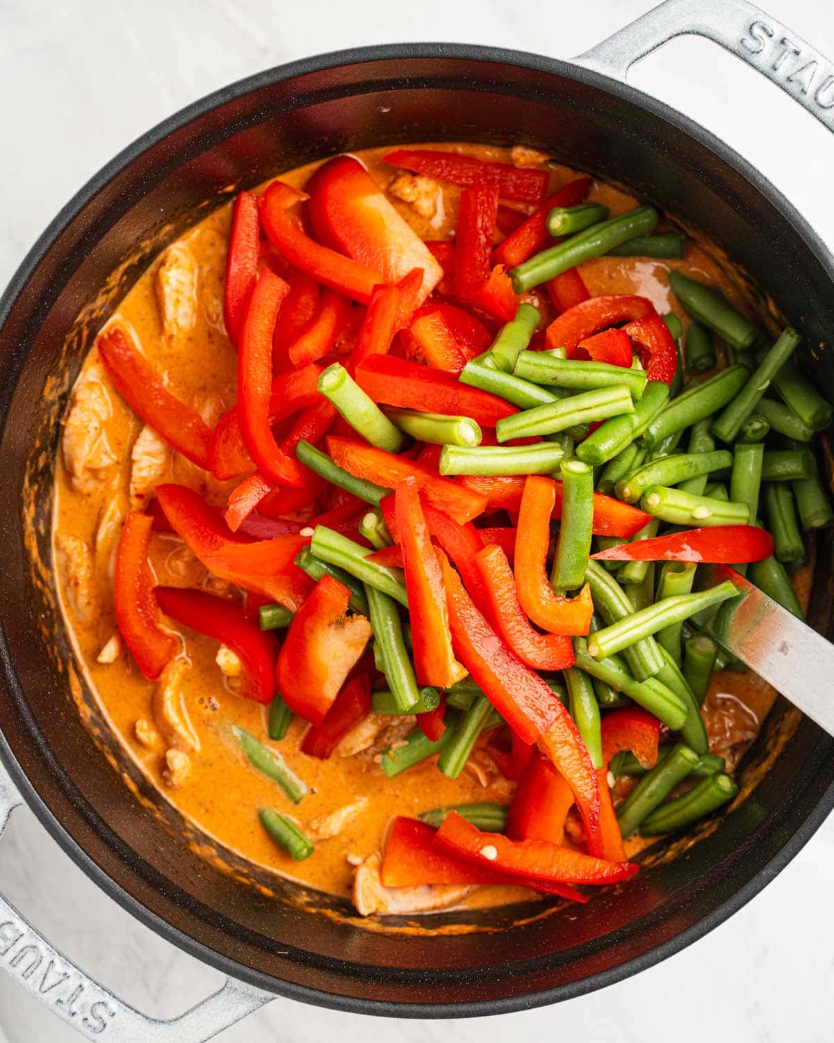green beans and sliced red peppers added to pot of curry.