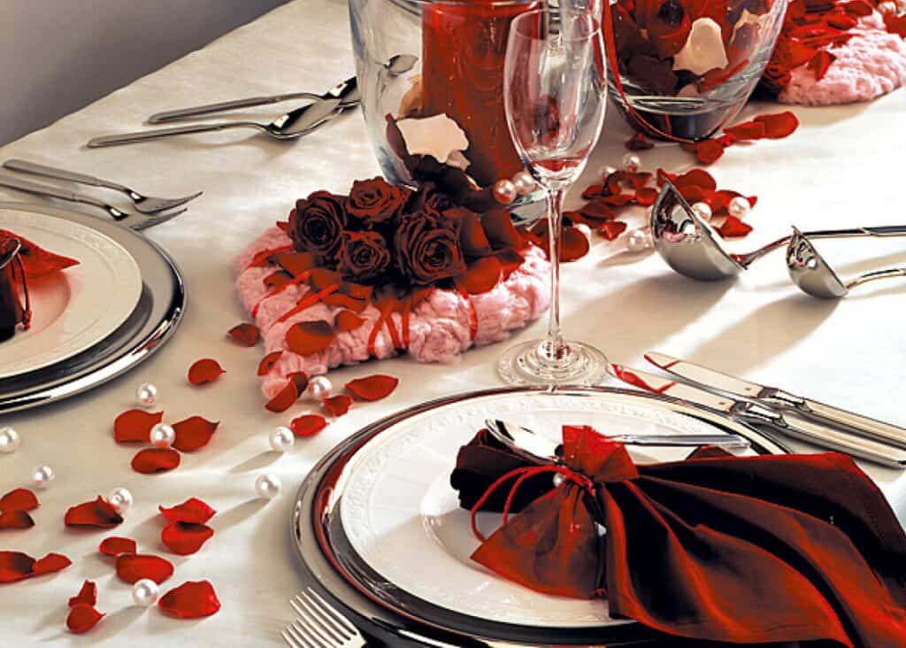 Eleganter Tisch mit Rosen, Kerzen und festlichem Geschirr.
