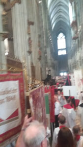 Historisches Inneres der Kirche mit Schützenbrüdern im Festumzug, farbenfrohe Trachten, festliche Atmosphäre, traditionelle Feierlichkeiten in Köln.