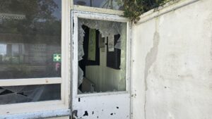 Zerbrochenes Fenster in einer alten Schützenhalle mit Kerben und unordentlicher Umgebung.