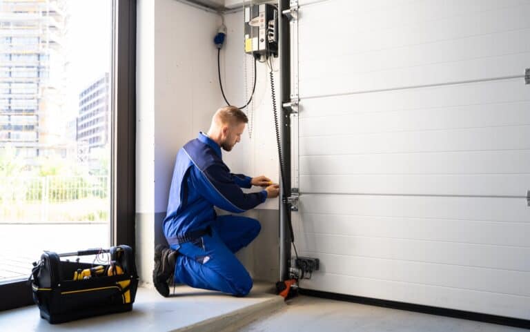 Man in blue uniform working on garage door track