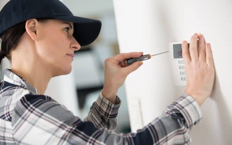female technician installing security system using screwdriver