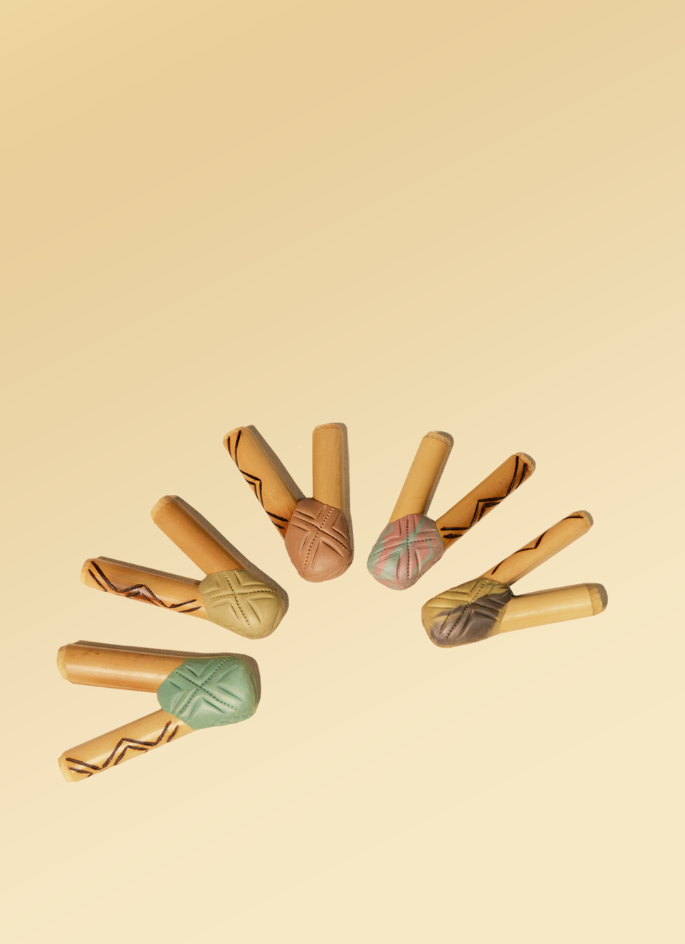 Colorful wooden rainsticks with tribal patterns, traditional musical instruments used in Shaman Hape rituals, arranged in a semi-circle on a beige background.