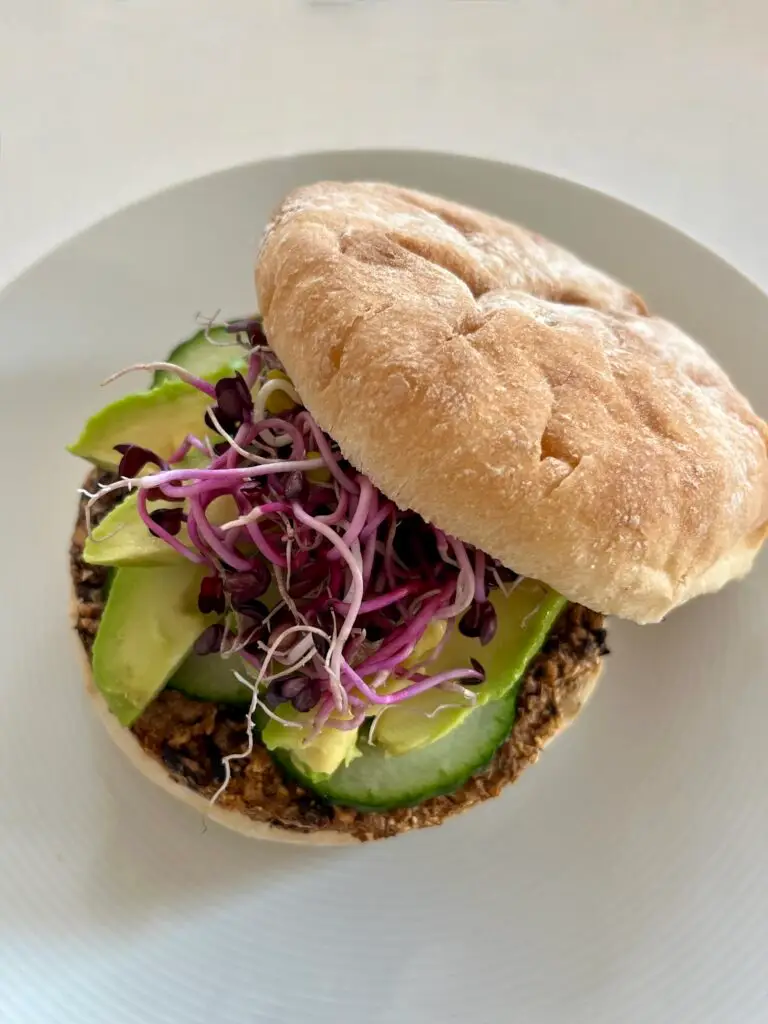 top view of vegan burger with toppings of bean sprouts, avocado and cucumbers