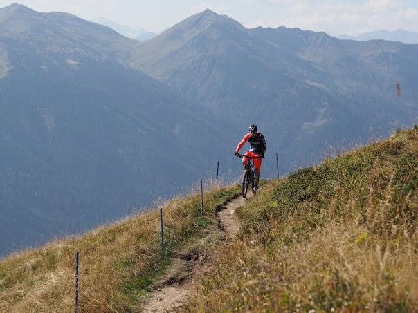 Mountainbiker auf schmalem Pfad in den Bergen.