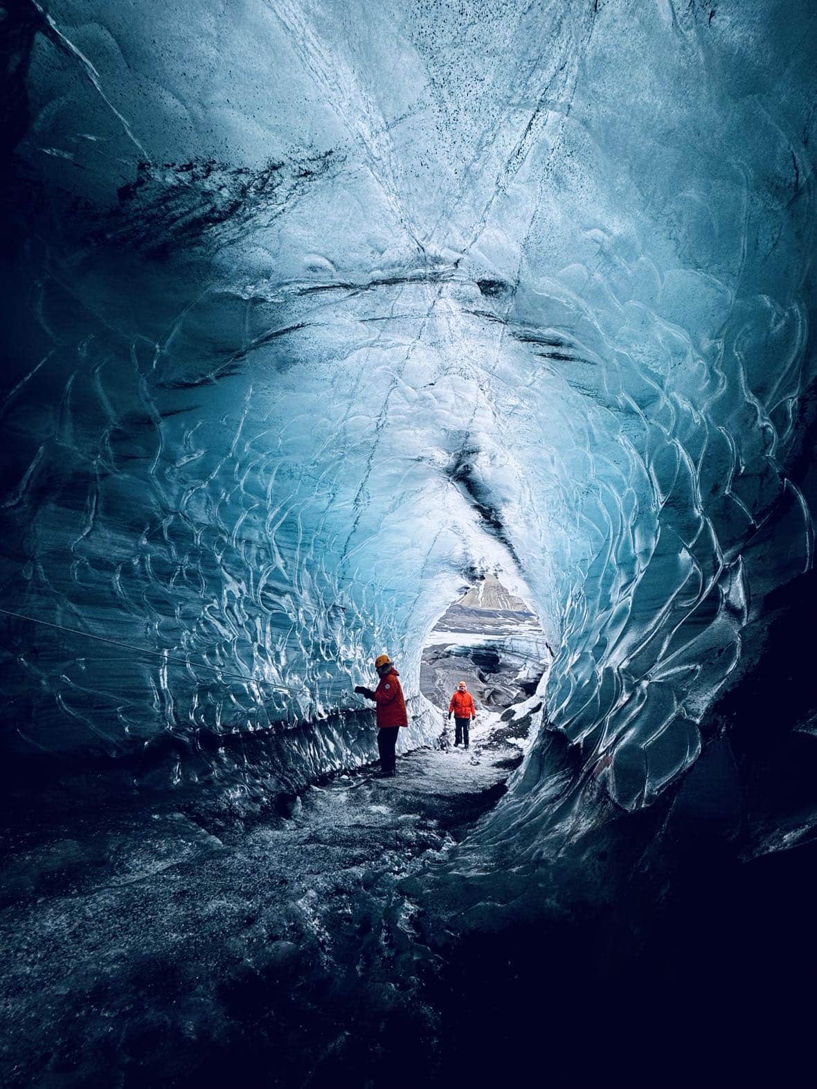 People standing inside Katla Ice Cave surrounded by blue ice