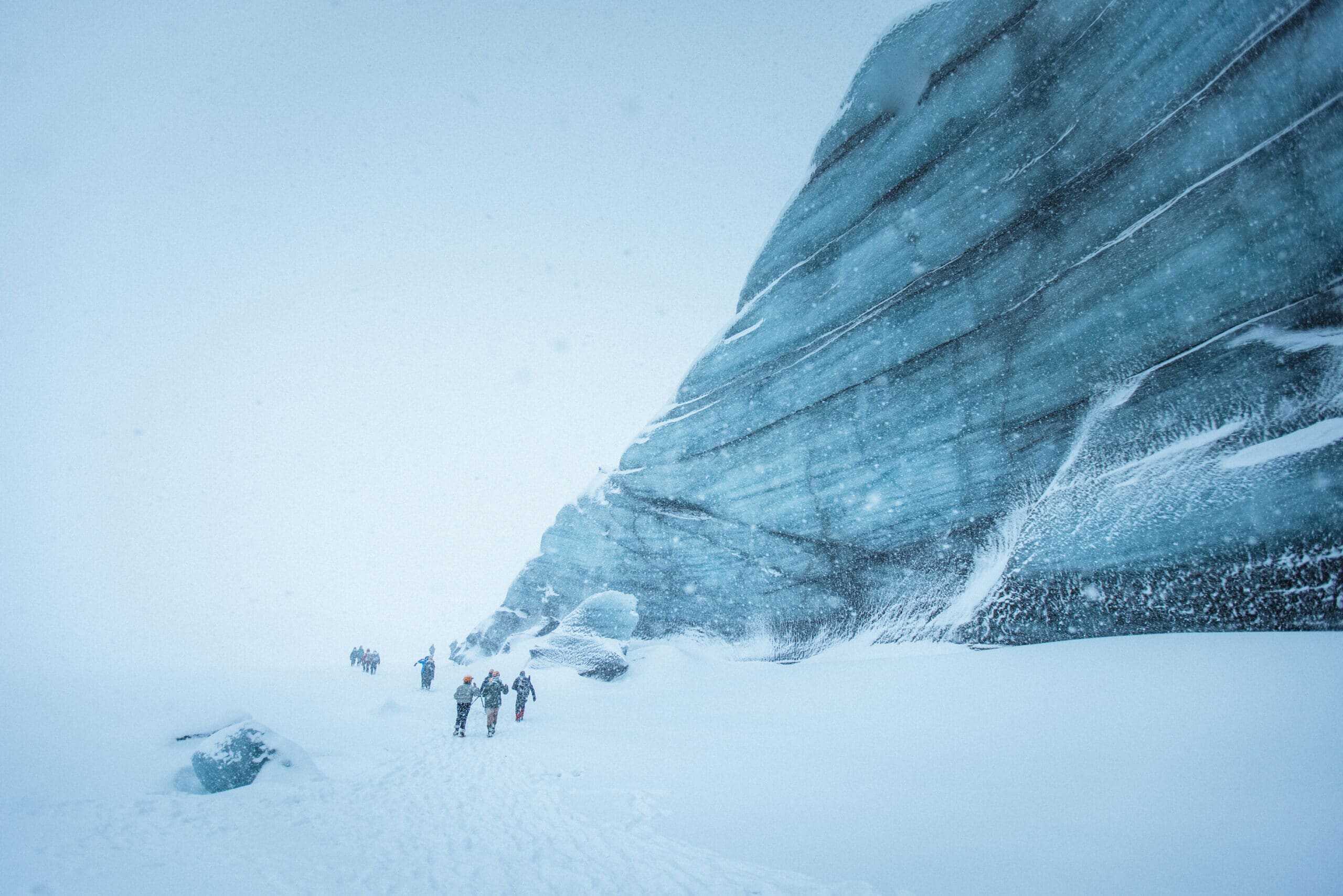 People in a snowstorm standing next the the ice of Katla.