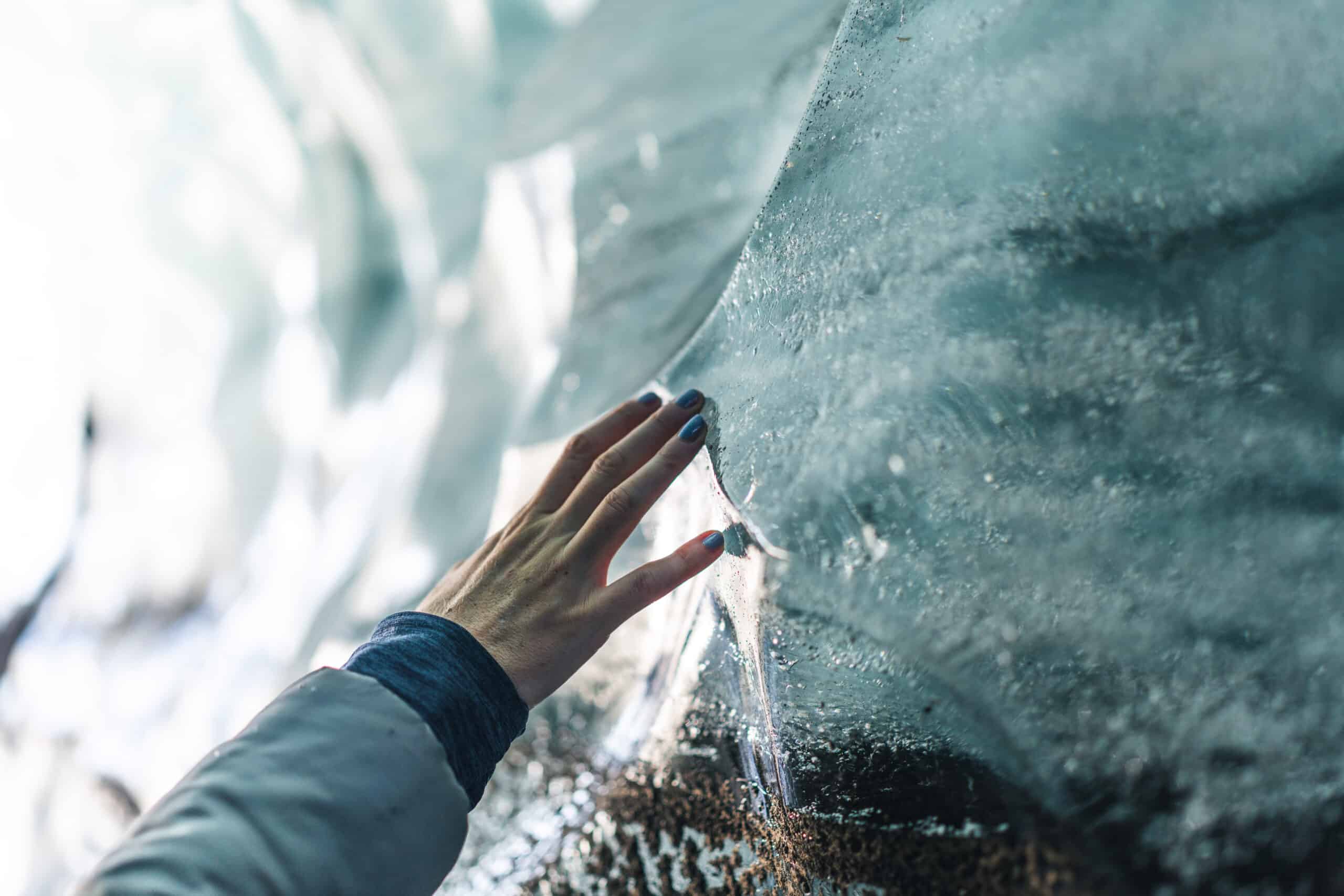 A hand touching the ice of Katla Ice Cave.