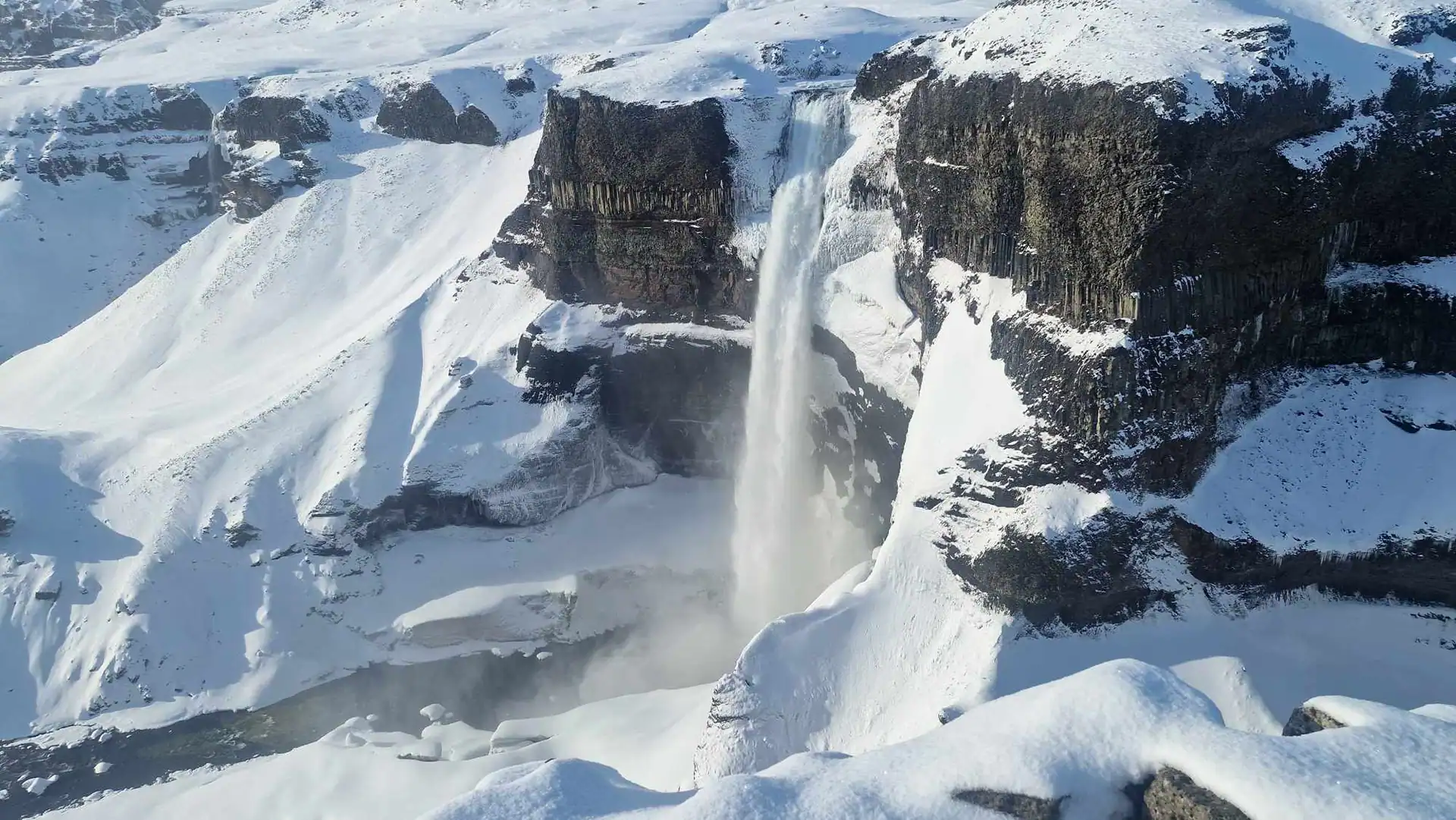 A long waterfall surrounded with snowy rocks