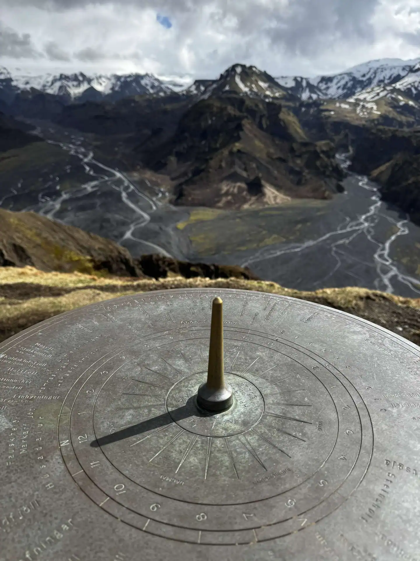 A large compass in the foreground with a view over multiple mountains and lakes in Thorsmork Iceland