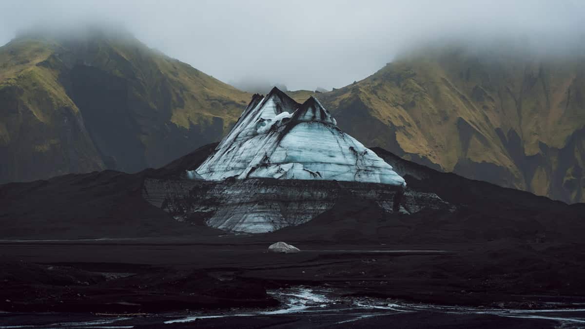 Icy mountain surrounded by mossy mountains on a Katla Ice Cave Tour