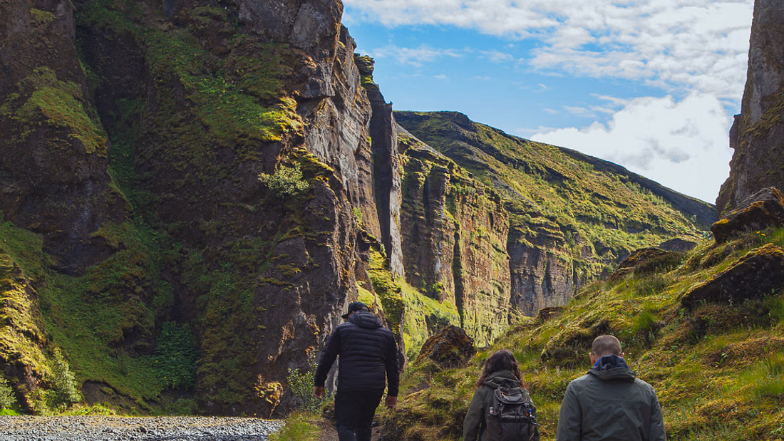People standing in the Thorsmork valley with green cliffs standing before them on multiday tour with Southcoast Adventure