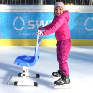 Mädchen beim Eislaufen mit Eislaufschuhen und Helm auf Eisbahn.