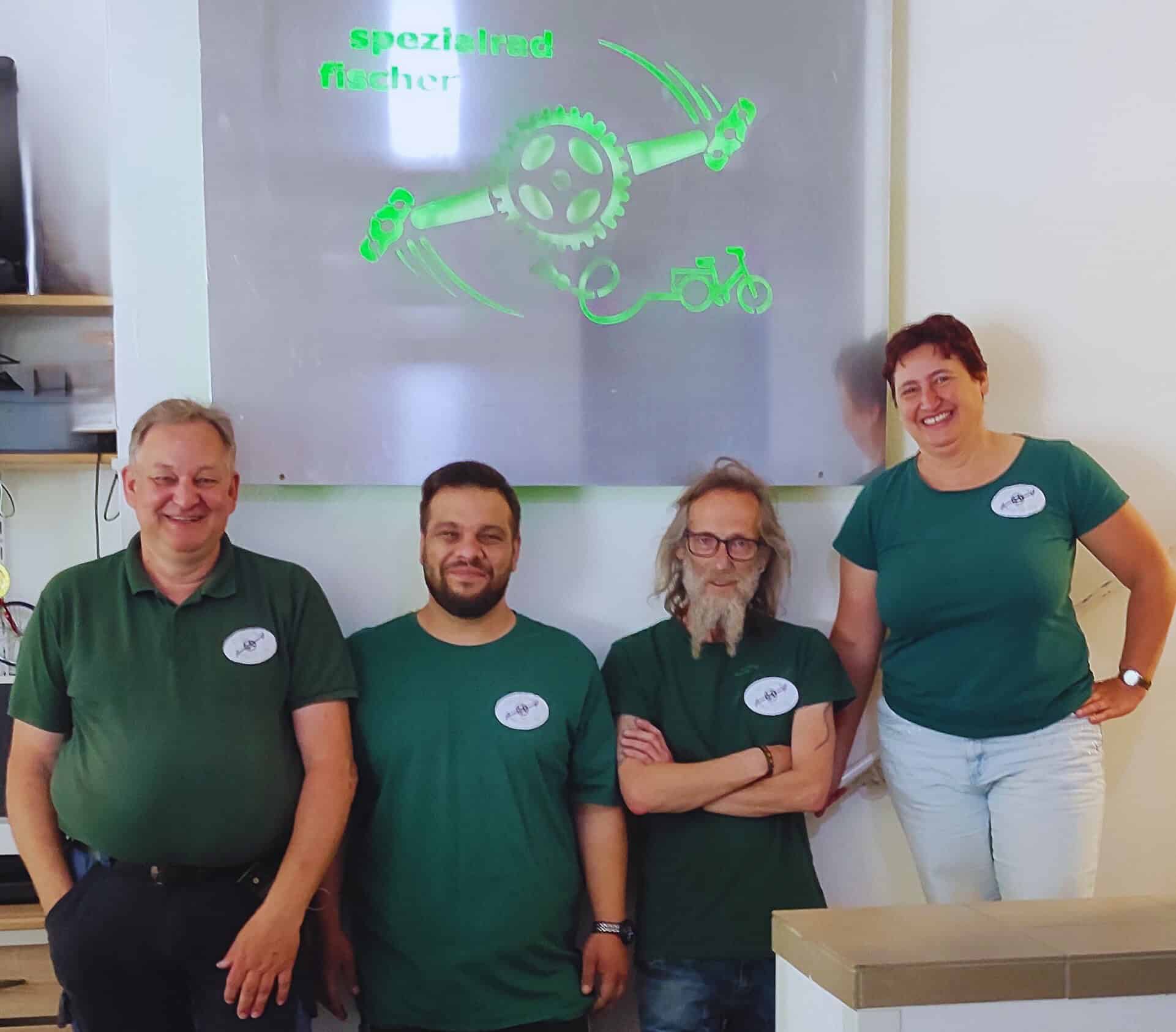 Spezialrad Fischer Team in Dasing Teamfoto bei Spezialrad Fischer in Dasing mit Fahrrad-Logo im Hintergrund.