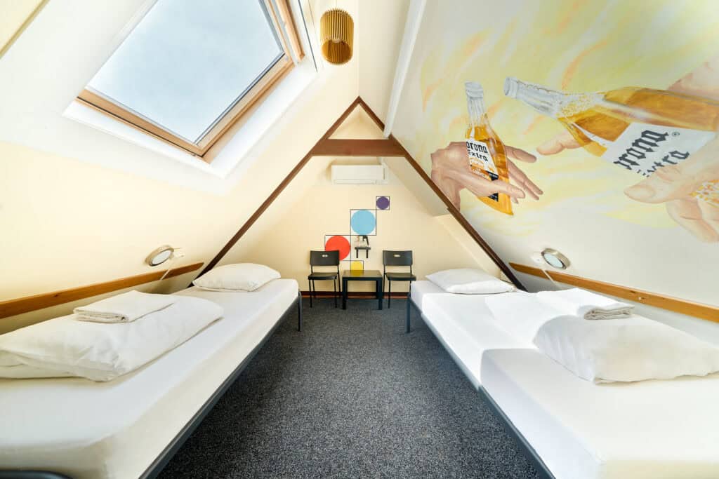 Modern dorm room at Flying Pig Uptown Hostel with two single beds and colourful wall art.
