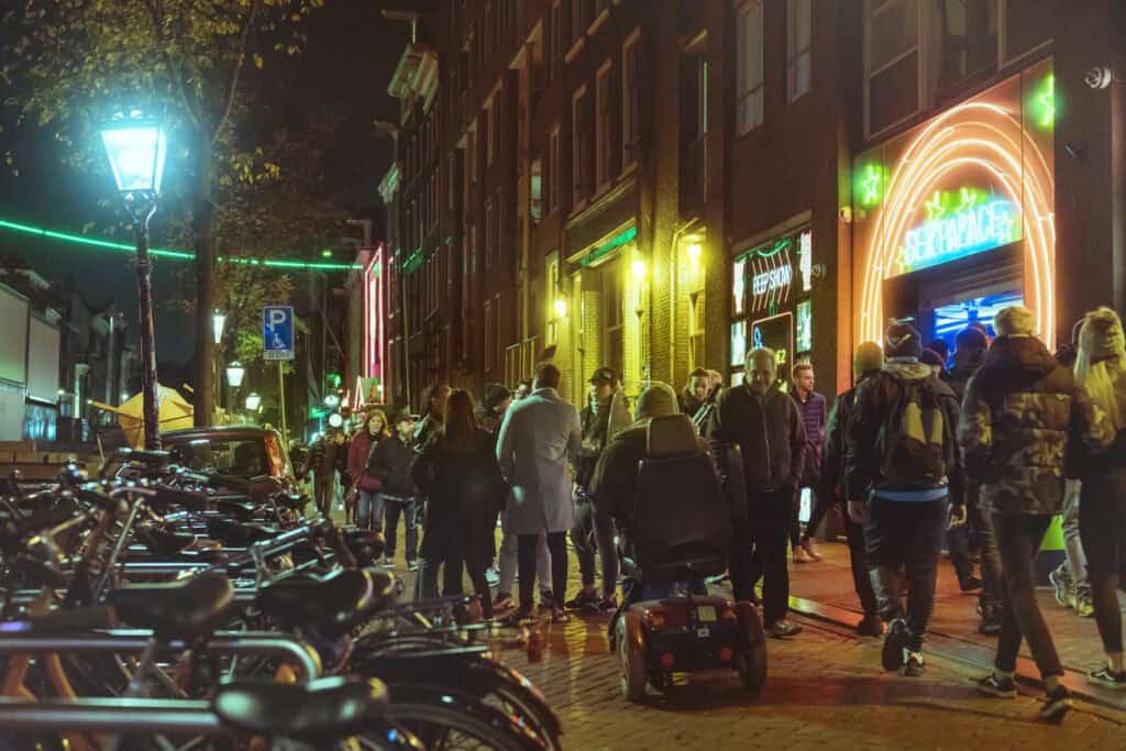 Vibrant night scene at Uptown Hostel with neon lights and busy street crowd in Amsterdam.