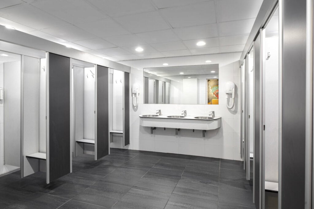 Clean hostel bathroom with individual shower cabins and a spacious mirror, perfect for guests at Fly.