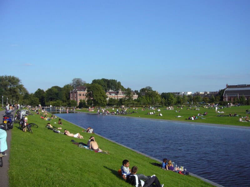 View of a city park near The Flying Pig Downtown hostel with people relaxing by the river.