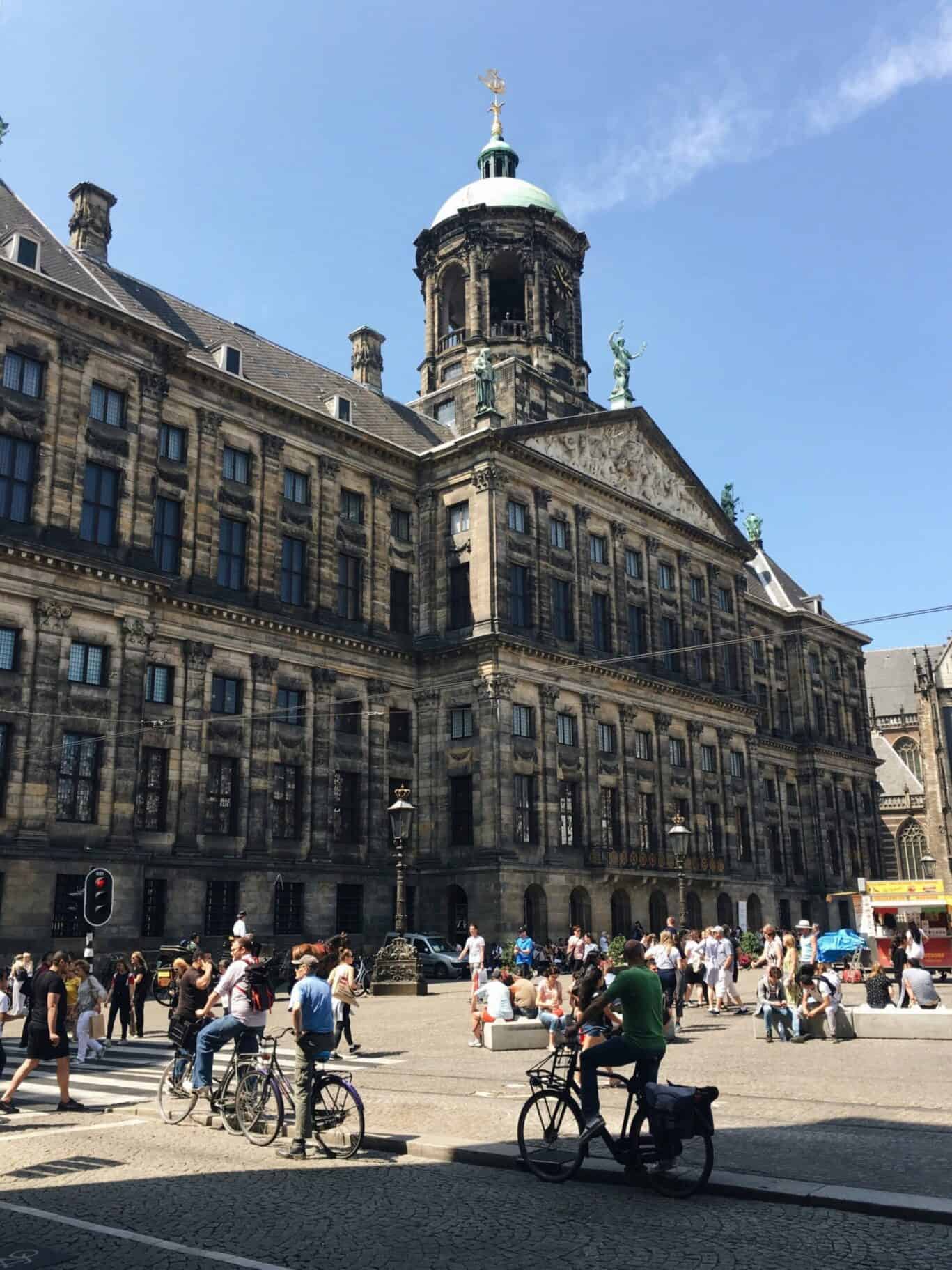 View of a historic city hall with people and cyclists in the foreground at The Flying Pig Downtown.